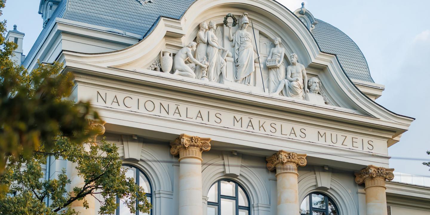 Latvijas Nacionālā mākslas muzeja ēkas fasādes skulpturālā grupa un uzraksts “NACIONĀLAIS MĀKSLAS MUZEJS”.