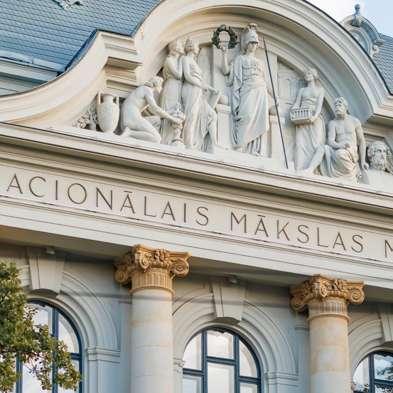 Latvijas Nacionālā mākslas muzeja ēkas fasādes skulpturālā grupa un uzraksts “NACIONĀLAIS MĀKSLAS MUZEJS”.
