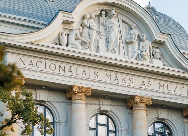 Latvijas Nacionālā mākslas muzeja ēkas fasādes skulpturālā grupa un uzraksts “NACIONĀLAIS MĀKSLAS MUZEJS”.