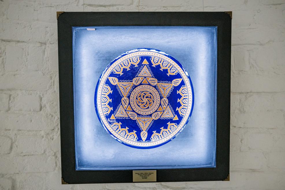 Close-up of the pole sculpture showing braided strands hanging from a symbolic golden ornament.