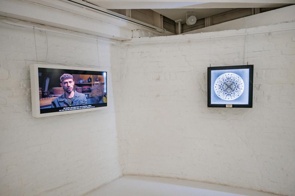 Telpas centrā uz statīva novietots tradicionāls Krimas tatāru karogs ar zirga spalvām, abās pusēs redzami kaligrāfijas ruļļi.