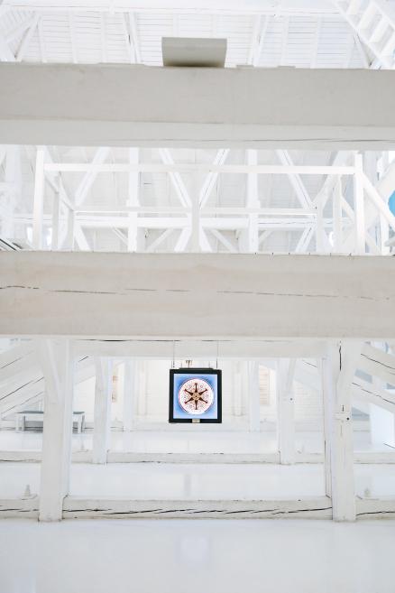 Illuminated ceramic plate with a brown and yellow geometric star motif hanging in the gallery.