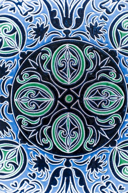 Symmetrical ornamental design in blue and green on a plate surface reflecting traditional Crimean Tatar symbolism.