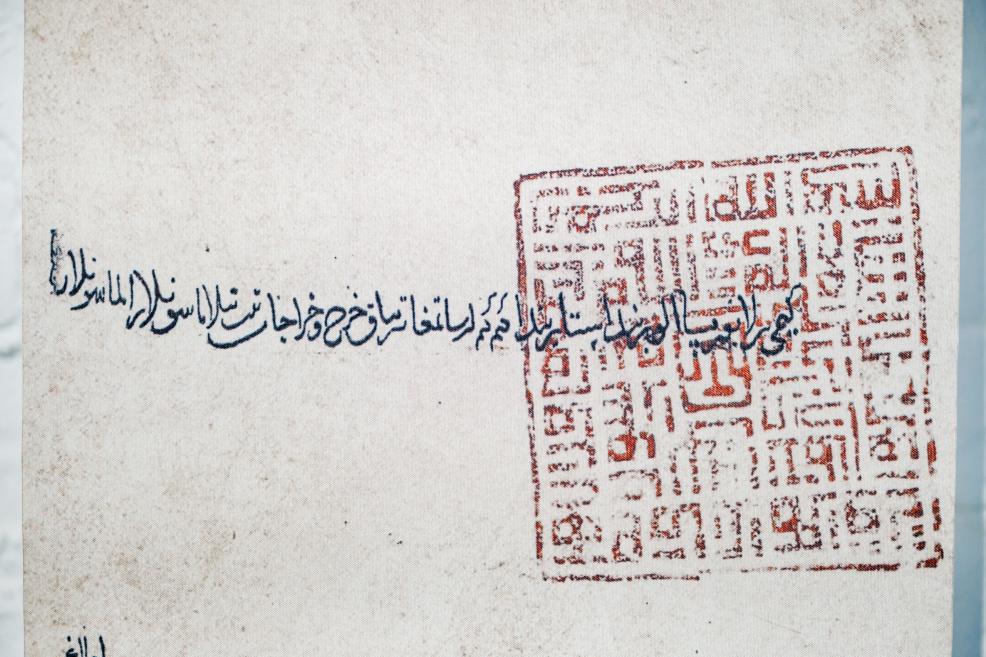 Historical document with Arabic calligraphy and a red seal displayed in the exhibition “Qalqan. Symbols of Crimean Tatars.”