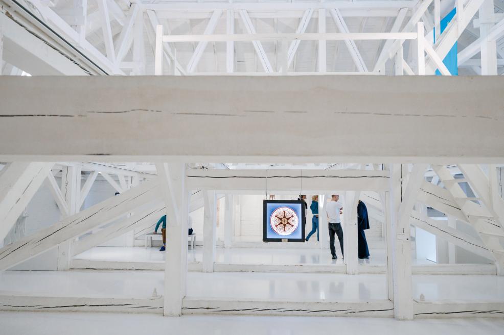 Visitors walking among white wooden beams and illuminated panels in the exhibition “Qalqan. Symbols of Crimean Tatars.”
