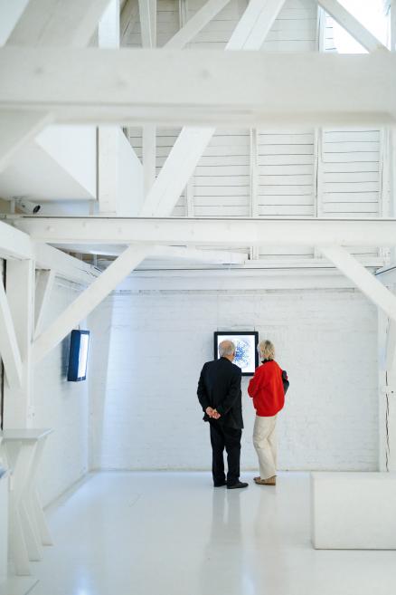 Apmeklētāji vēro digitālus mākslas darbus.