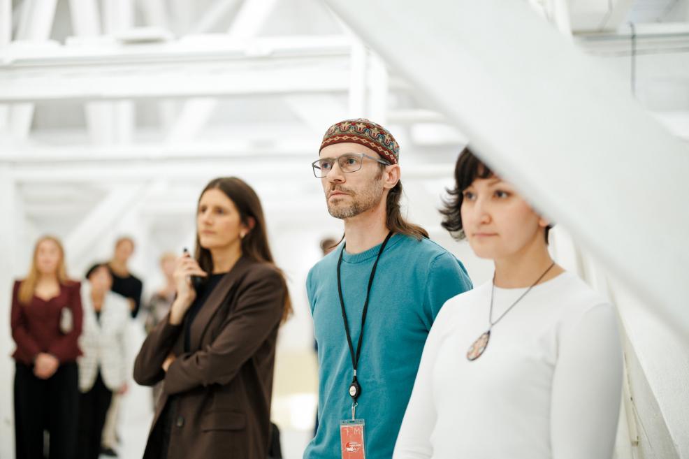 Apmeklētāji muzeja izstādes atklāšanā uzmanīgi klausās runātājus.