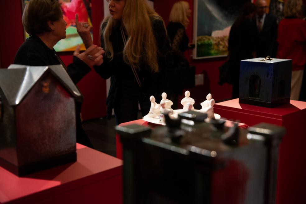 Visitors converse near small ceramic sculptures at the exhibition.