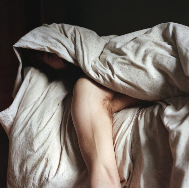 A photograph of a fragment of a man's hand under a blanket.