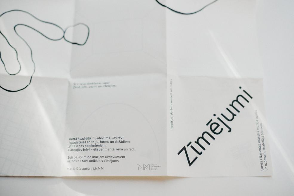 Balts papīra izdevums ar melnām līnijām un tekstu, uz kura redzams liels slīps nosaukums Zīmējumi.