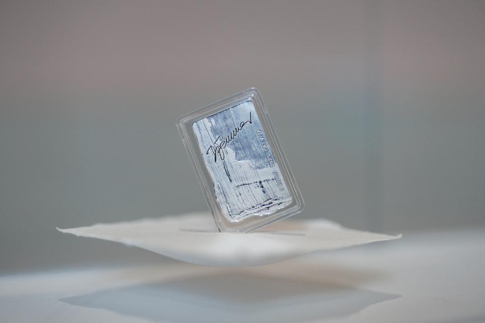 A close-up of a 5 euro commemorative coin with Džemma Skulme’s signature in a transparent case.