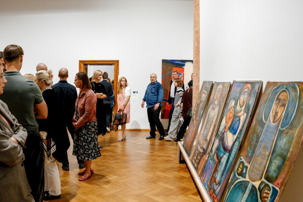 Museum visitors line up to view Džemma Skulme’s paintings displayed on the floor.