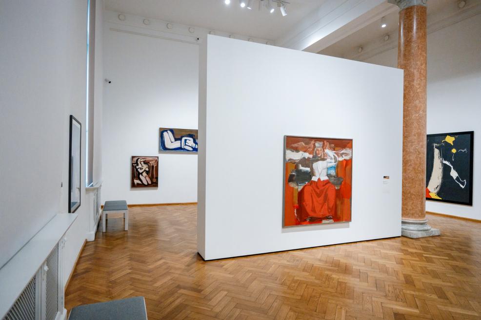 In the exhibition hall, paintings of female figures and vivid color field compositions are displayed on a white wall.