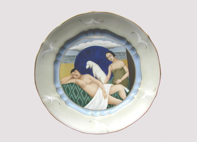 Painted porcelain plate with two women and a white dog in a beach scene with the sea and an umbrella.