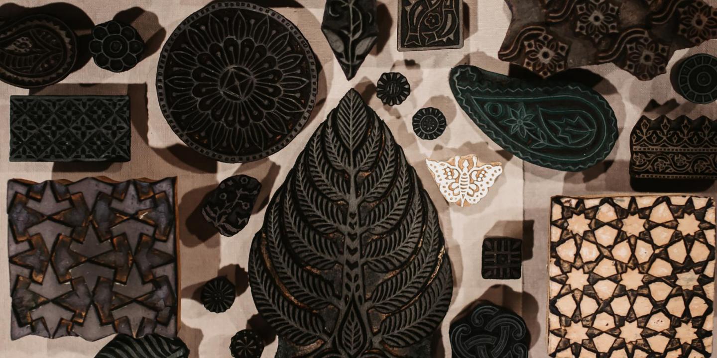 Uz galda izvietoti dažādu formu un rakstu koka spiedogi tekstila apdrukai.