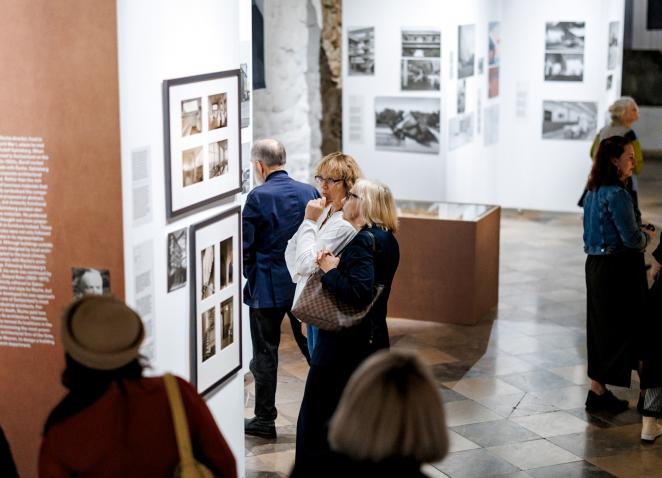 Apmeklētāji iepazīstas ar fotogrāfijām un teksta ekspozīciju plašā izstāžu zālē.