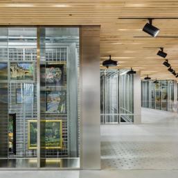 The collection storage of the Latvian National Museum of Art with metal grid structures and paintings visible behind a glass wall.