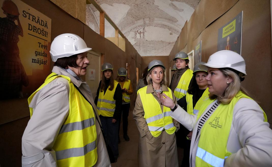 Site visit – people wearing helmets and safety vests observe the building renovation process.