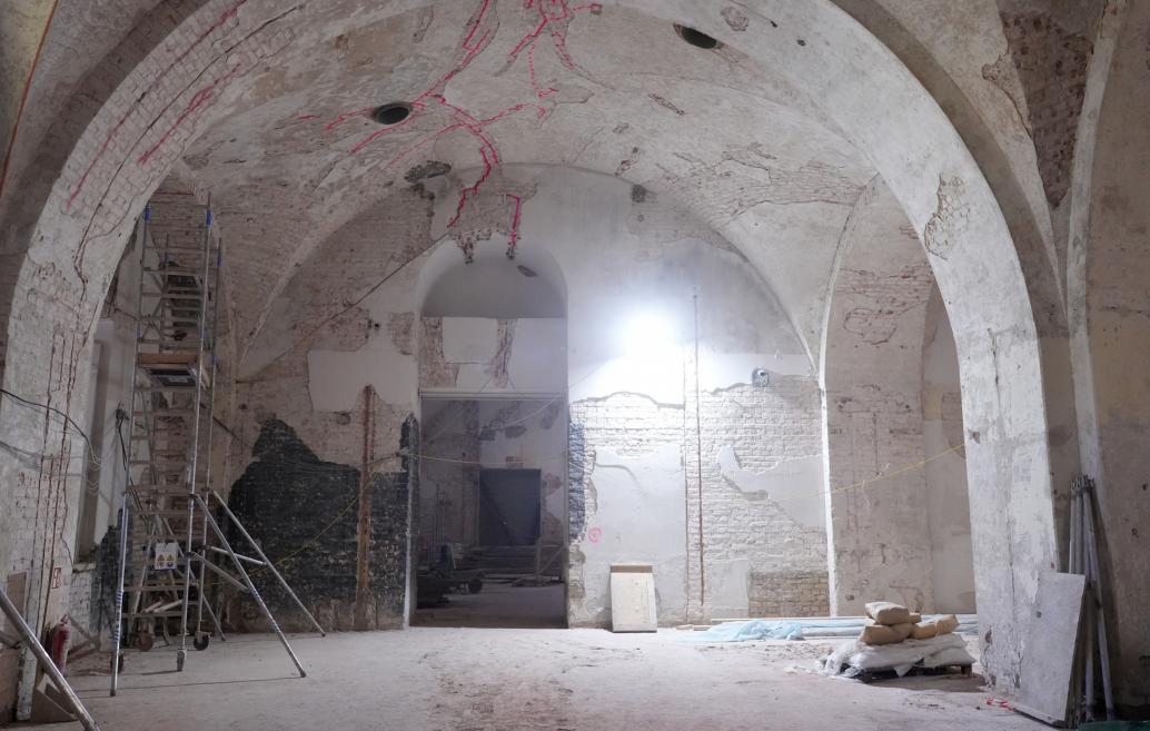 Interior view showing exposed brickwork, scaffolding, and construction equipment.