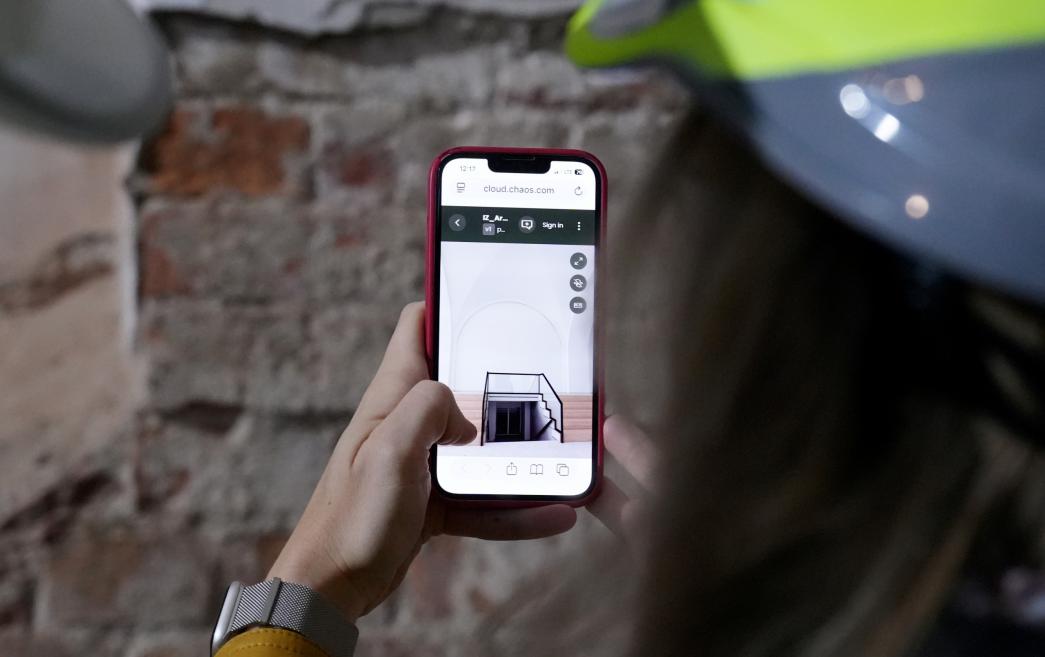 Person wearing a safety helmet views a digital visualization of the site on a smartphone.