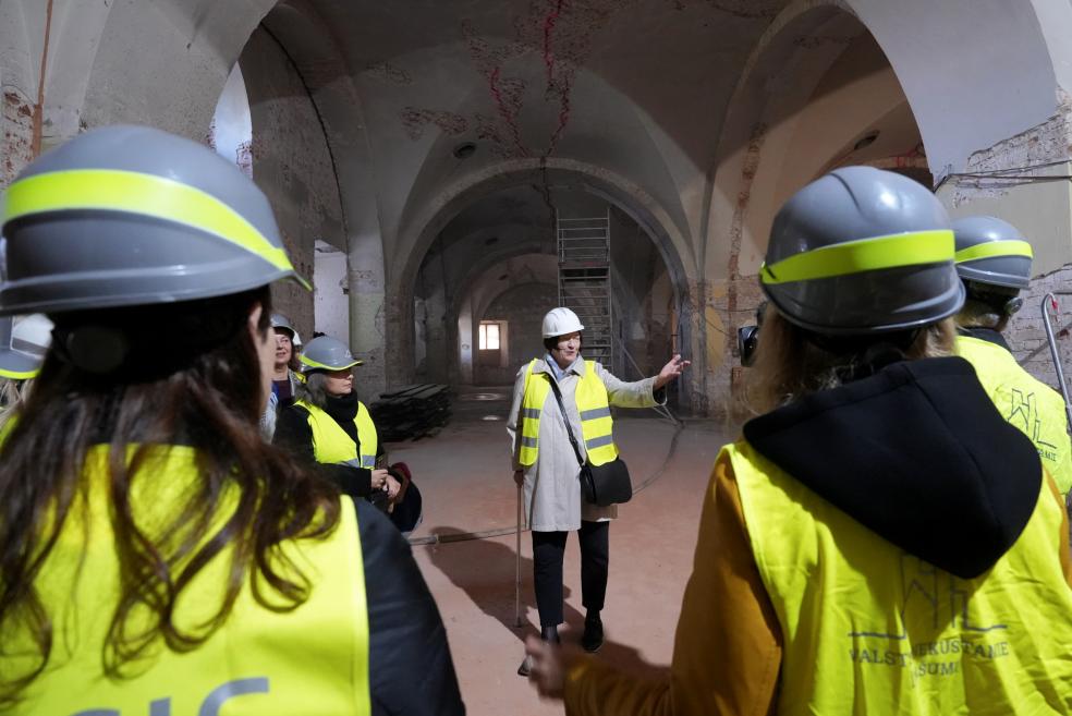 Tour participants wearing helmets and safety vests listen to a presentation about the construction progress.