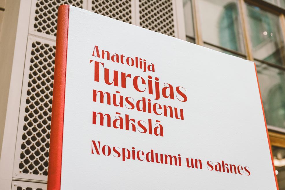 Red lettering with the event title displayed on a white wall.