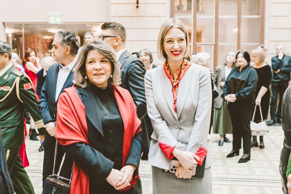 Two women smile while posing at the opening event.