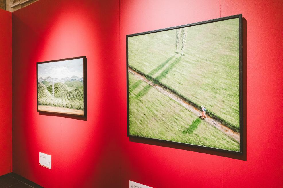 Landscape paintings depicting mountains and fields are displayed on red walls.