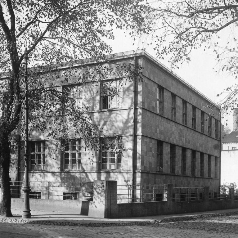 Historical black-and-white photograph of a modernist-style building in Riga, surrounded by trees with falling leaves.