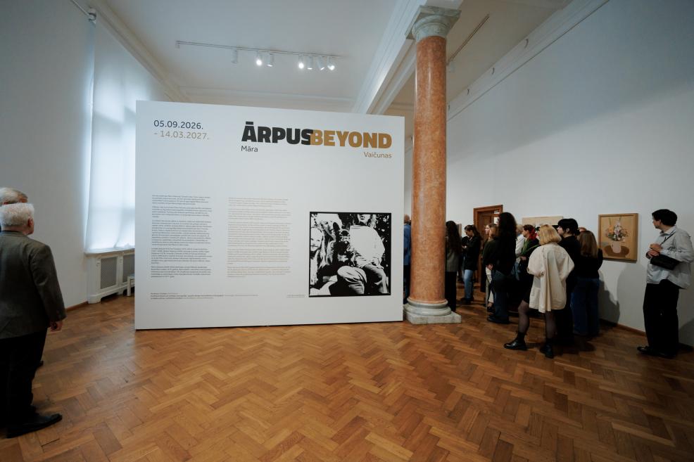 An exhibition panel reading ĀRPUS BEYOND stands in a museum gallery with visitors viewing the display among tall columns.