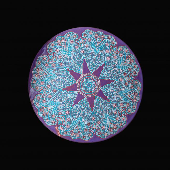 Apgleznots dekoratīvs šķīvis violetā tonī ar ziliem un rozā ornamentiem ziedu motīvos.