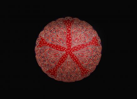 Red decorative plate with intricate ornaments on a black background.