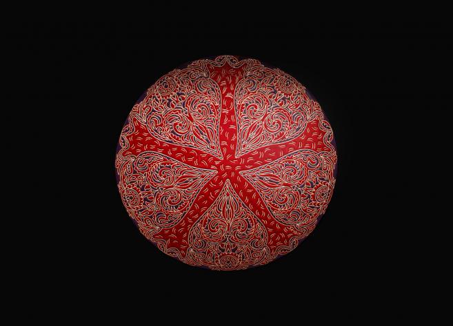 Red decorative plate with intricate ornaments on a black background.