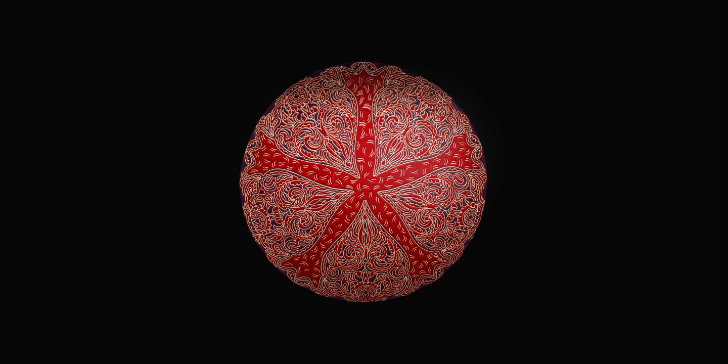Sarkans dekoratīvs šķīvis ar sarežģītiem ornamentiem uz melna fona.