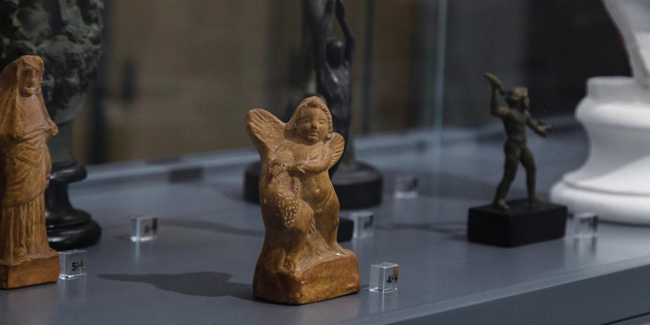 Tumšas skulptūras rokas paceltas pret spožu gaismas apli, kas atgādina sauli.