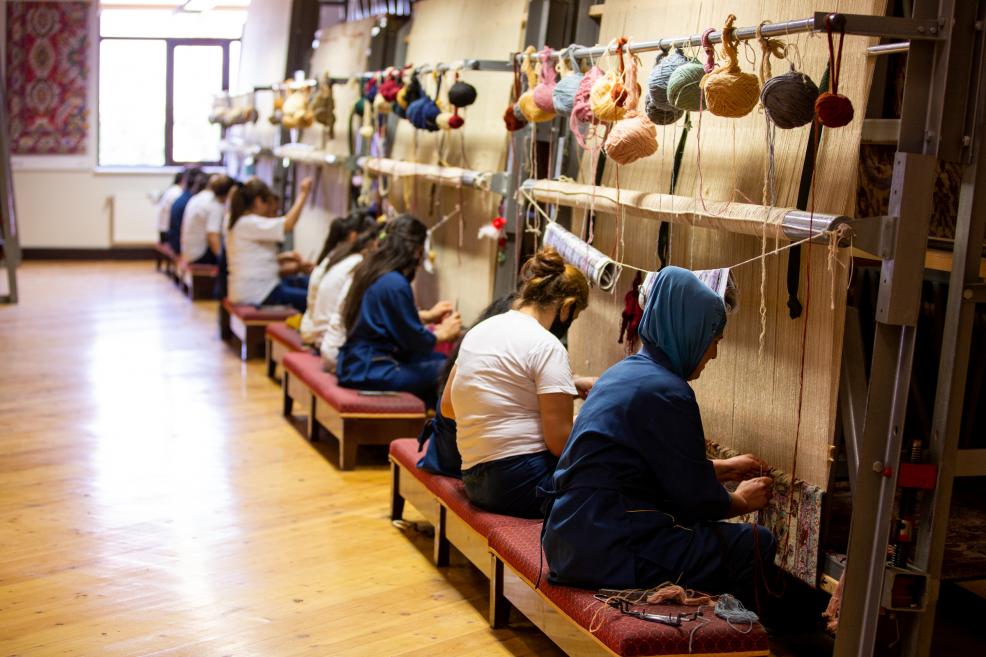 Weavers make carpets at the loom.