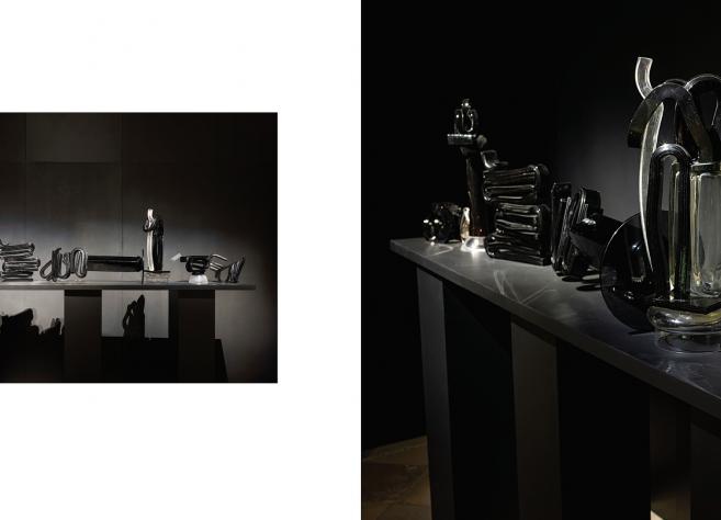 Tumšā ekspozīcijas telpā uz gara postamenta izgaismoti izvietoti melna un caurspīdīga stikla skulpturāli objekti, kas veido vienotu, ritmisku kompozīciju ar izteiktu gaismas un ēnas spēli.