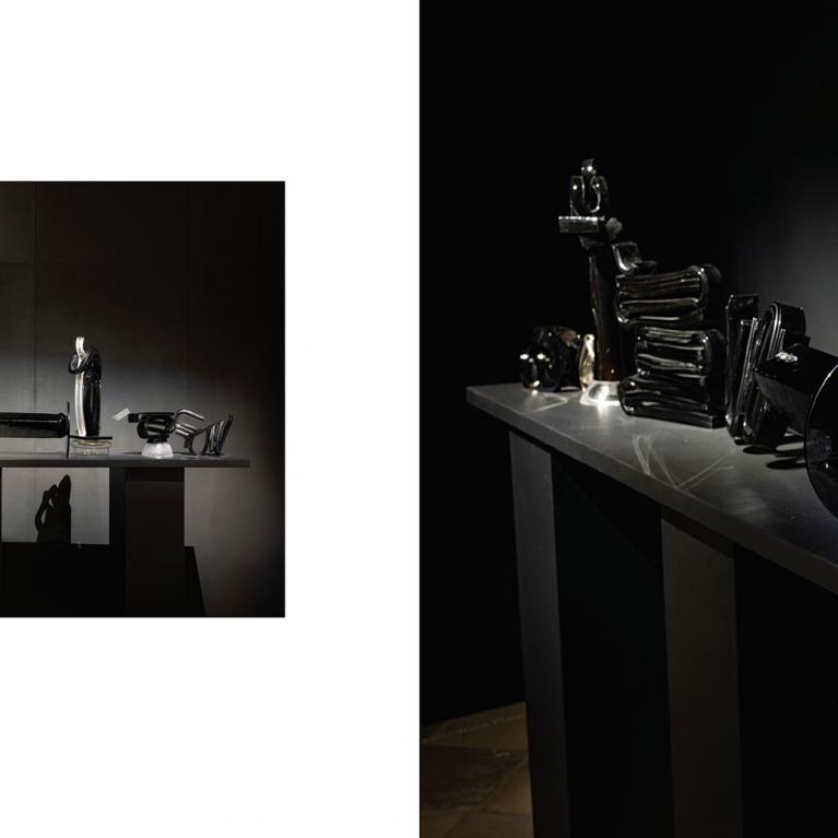 Tumšā ekspozīcijas telpā uz gara postamenta izgaismoti izvietoti melna un caurspīdīga stikla skulpturāli objekti, kas veido vienotu, ritmisku kompozīciju ar izteiktu gaismas un ēnas spēli.