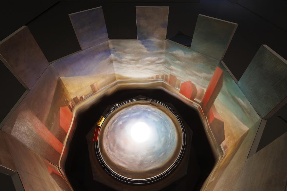 An installation at the exhibition, which is a moving train in a painted landscape