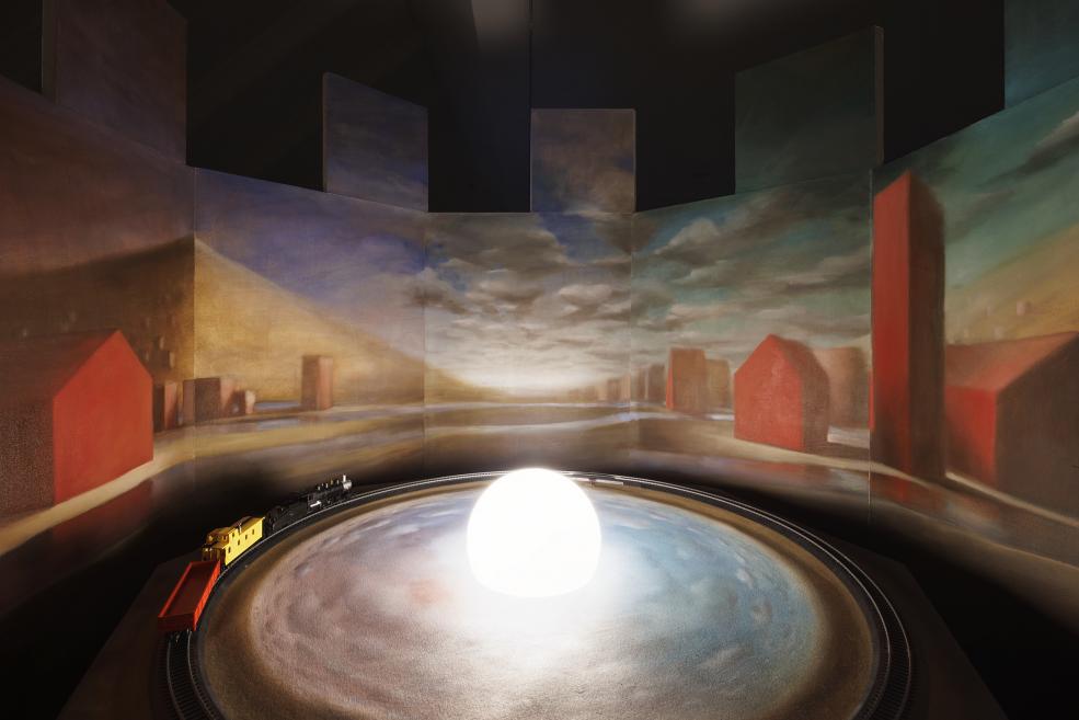 An installation at the exhibition, which is a moving train in a painted landscape
