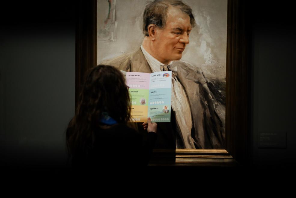 Apmeklētāja muzejā tur izglītojošu uzdevumu karti un salīdzina to ar vīrieša portretu gleznā ekspozīcijā.
