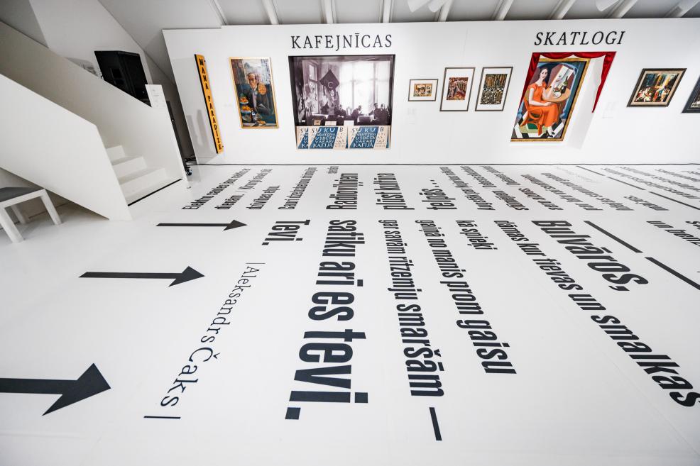 Exhibition display with paintings, wall headings and floor texts.