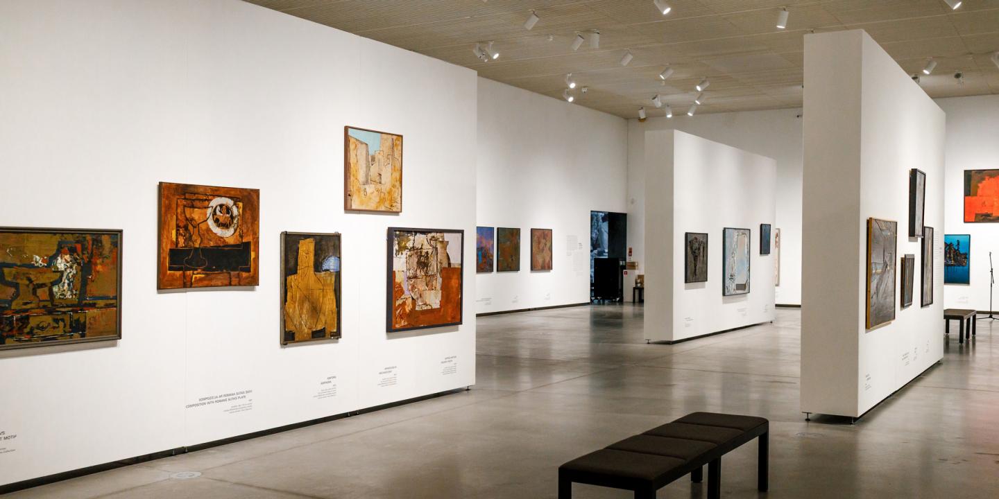 Muzeja izstāžu zāle ar vairākiem abstraktiem mākslas darbiem un soliņu apmeklētājiem.