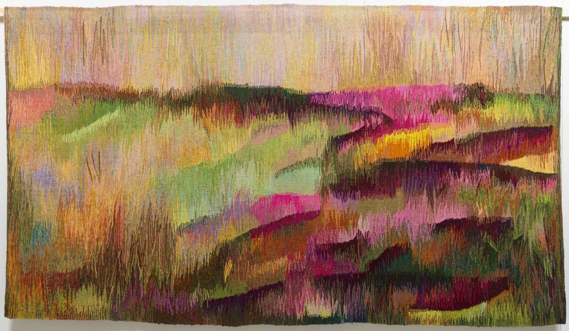 Colorful woven tapestry depicting an abstract landscape with vibrant pink, green, yellow, and earthy tones.