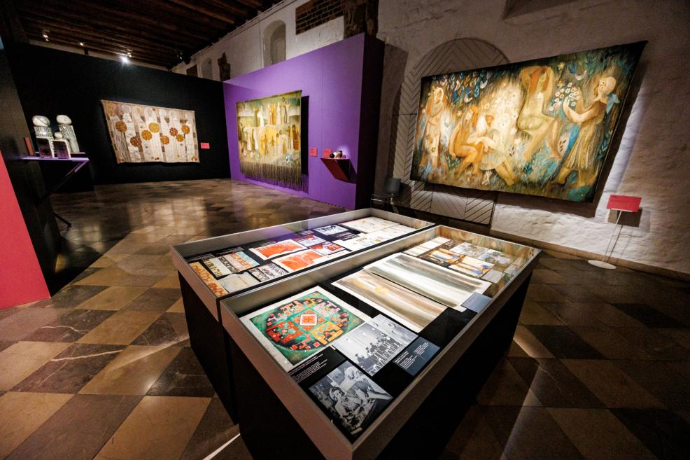 Muzeja izstāžu zāle ar pie sienām izvietotiem lielformāta tekstilmākslas darbiem un vitrīnās eksponētiem zīmējumiem un skicēm.