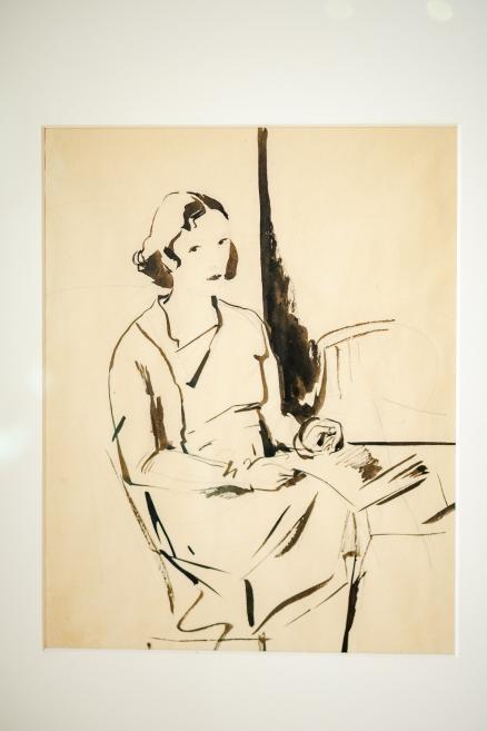 Melnbalts zīmējums, kurā attēlota sēdoša sieviete krēslā, viegli pagriezusies uz sāniem ar rokām klēpī.