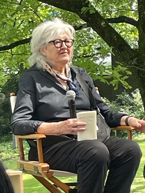 Conversation with a guest during an outdoor event, holding a microphone and a book.