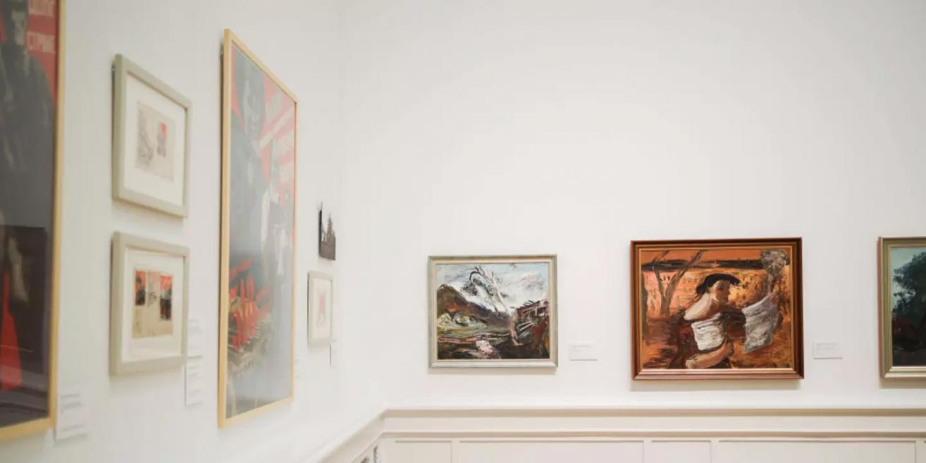 Izstādes fragments ar gleznām un plakātiem, kas ataino 20. gadsimta mākslas stilus un sociālistiskā reālisma motīvus.