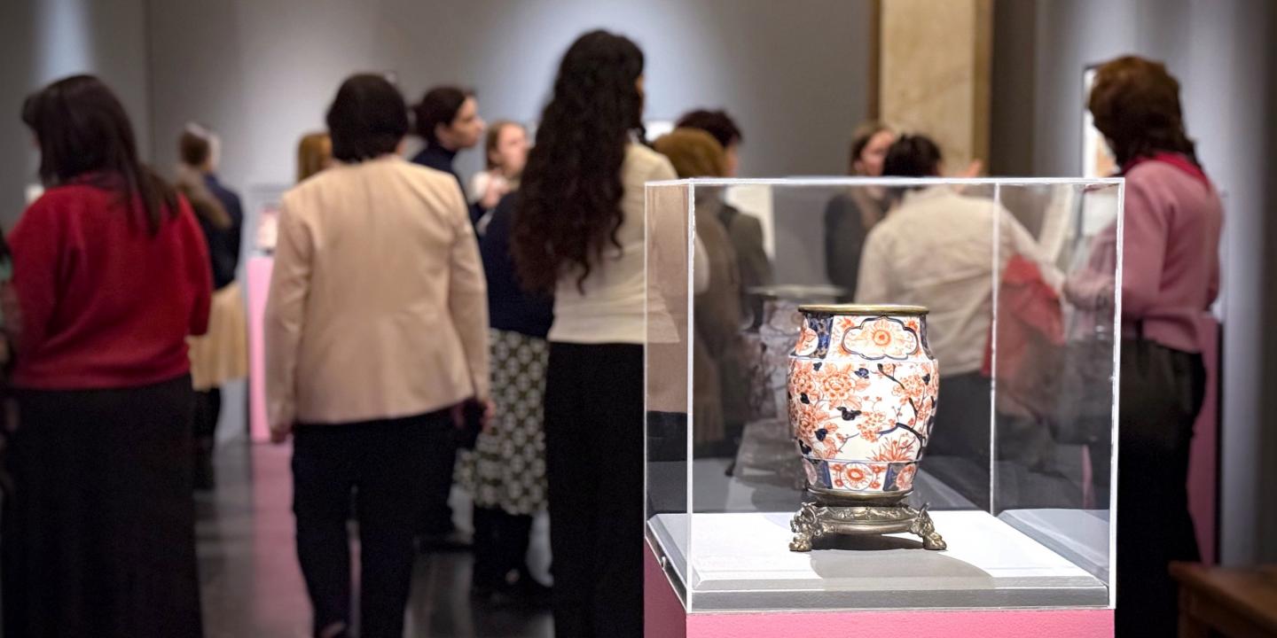 Japāņu grafikas darbs ar mūziķi, kas spēlē stīgu instrumentu, dekoratīvu rakstu un ziedu fonā.