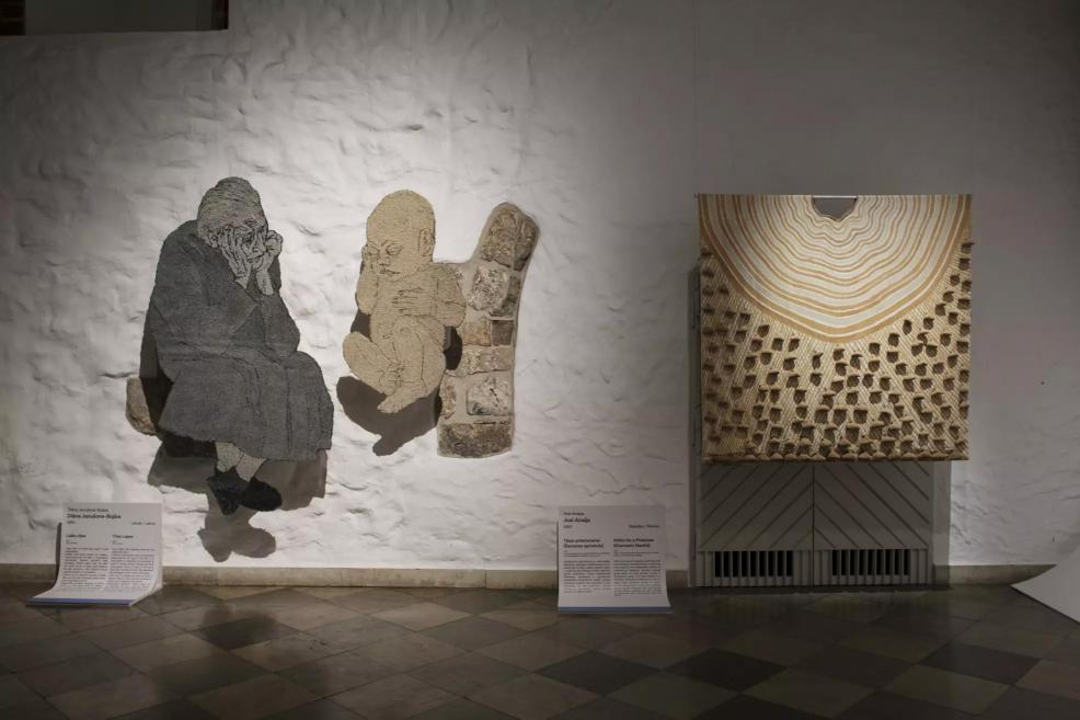 Textile works depicting a grieving woman and a baby next to a geometric fabric with concentric lines and structures.